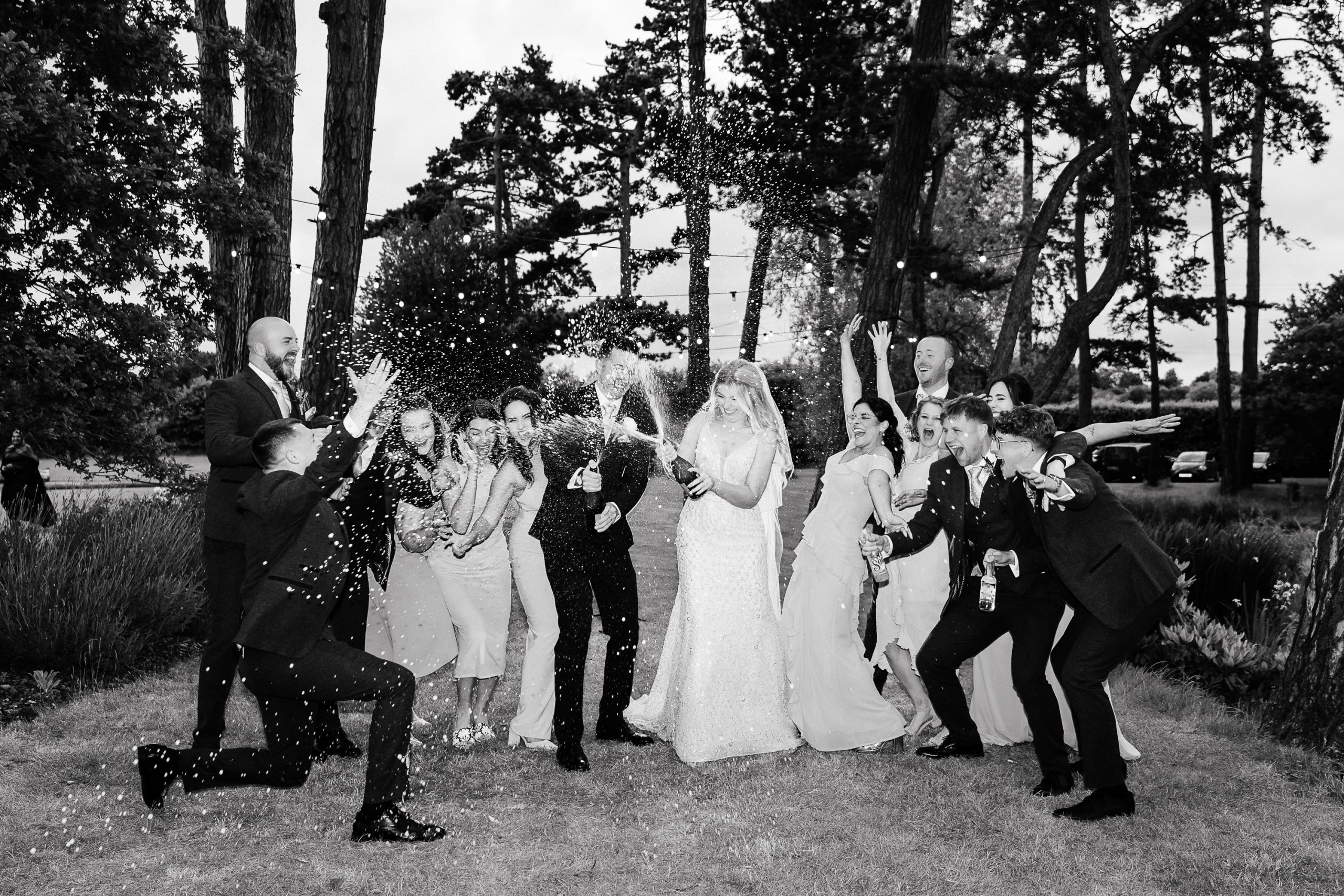 Editorial Wedding Photographer Hertfordshire | Shrigley Photography & Films - SHRIGLEY Bridal party on a tree lines grassy path spraying champagne and laughing - Hertfordshire Wedding Photographer & Videographer | Shrigley Photography & Films