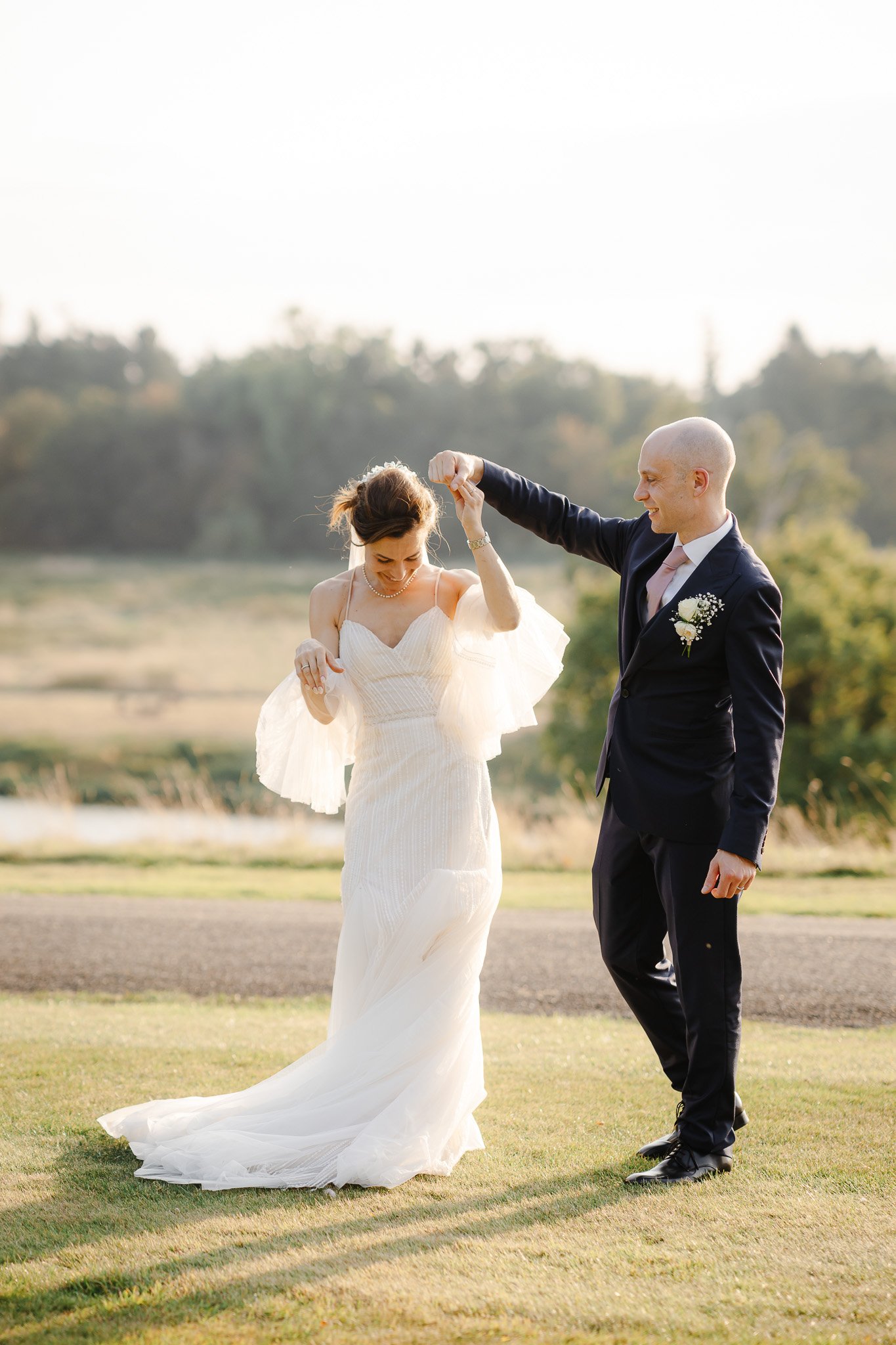 Hertfordshire Wedding Photographer & Filmmaker54 - SHRIGLEY Man and woman in wedding outfits in the evening sunshine smiling and doing a twirl - Hertfordshire Wedding Photographer & Filmmaker - Brocket Hall Wedding - Shrigley Photography & Film