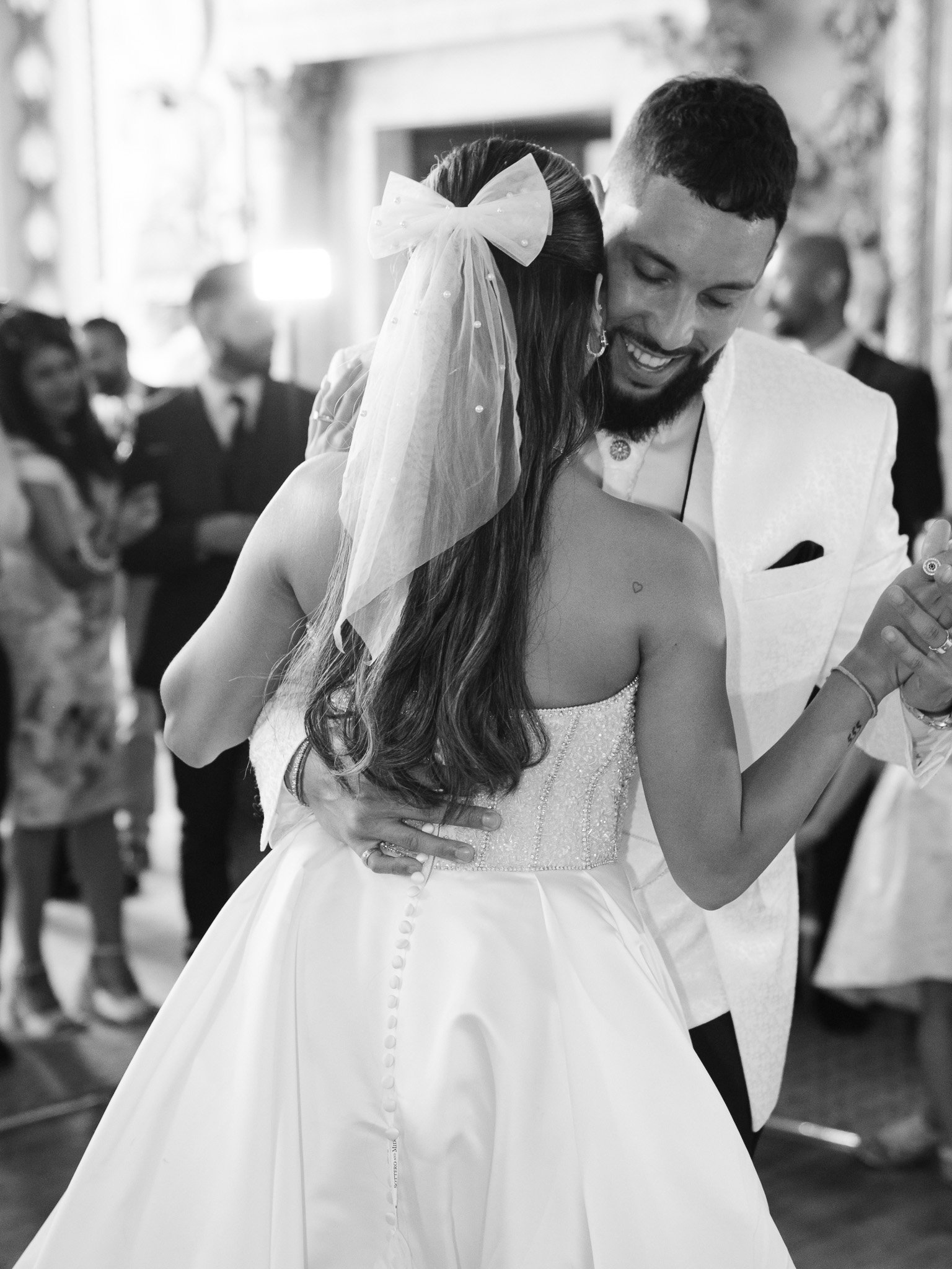 Hertfordshire Wedding Photographer - Shrigley Photography & Films - SHRIGLEY Bride & Groom dancing ith man smiling into the crook of brides neck with a bow in her hair - London Wedding Photographer & Filmmaker at Moor Park | Shrigley Photography & Film